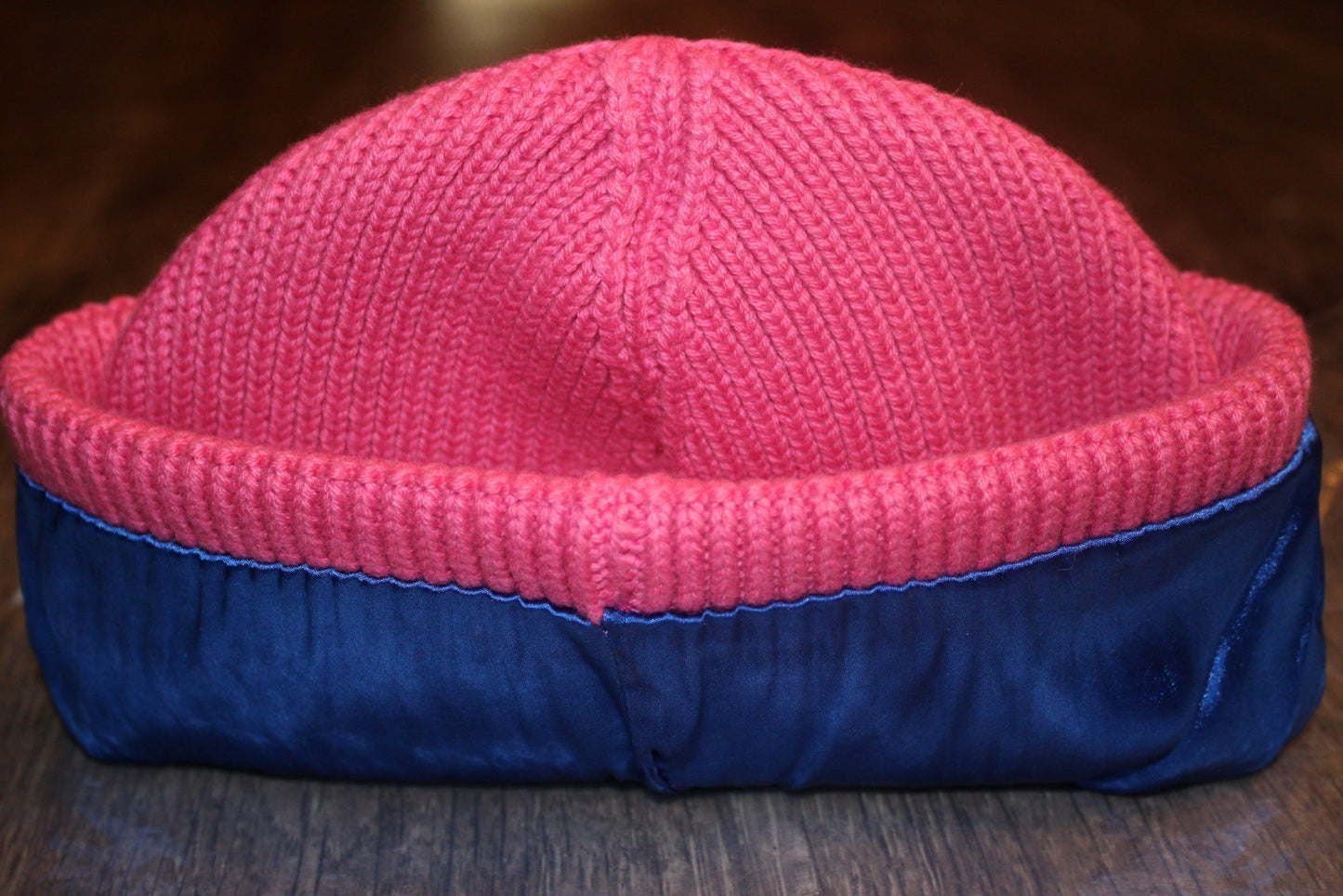 Pink beanie with blue lining on a wooden surface