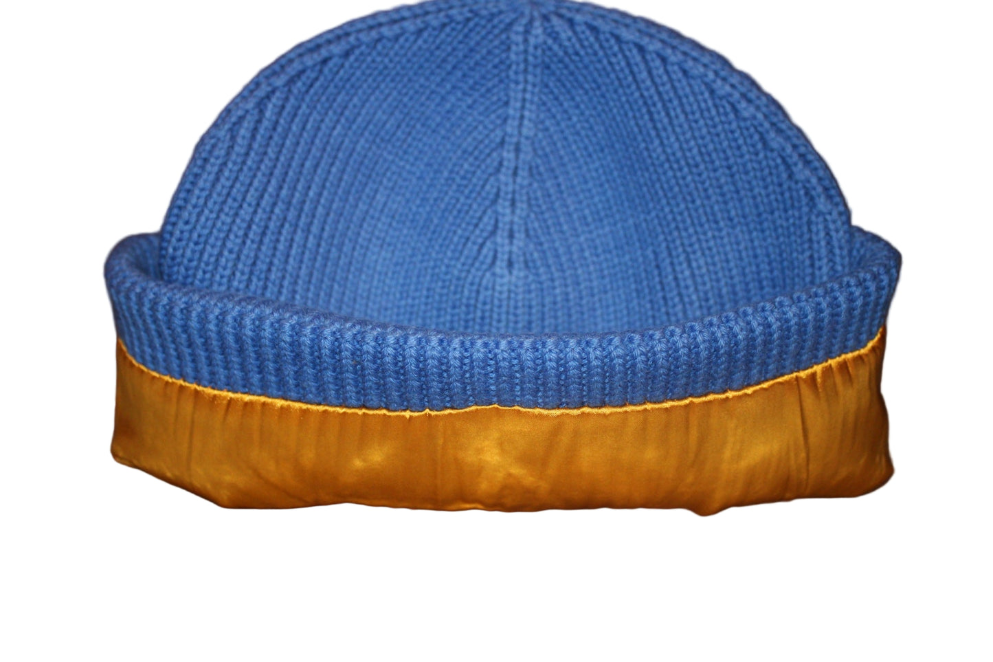 Blue knit beanie with gold lining on a wooden surface
